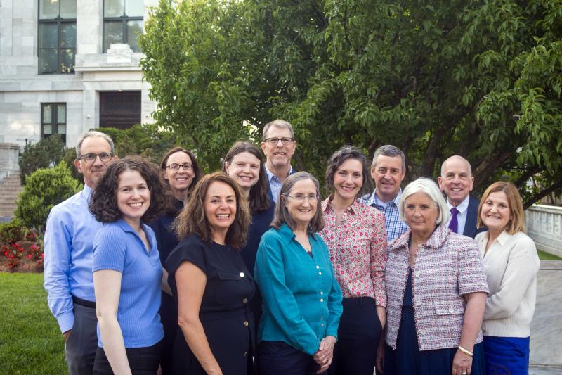 a group of adults smiling in front of a tree and building